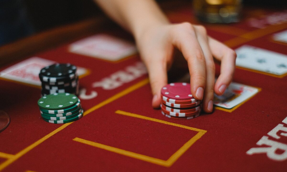 Hand moving real casino chips on a red gaming table for an NZ$15 deposit