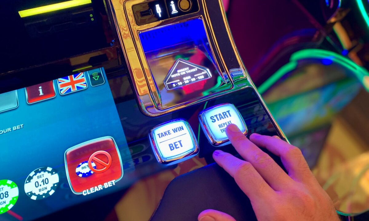 Player selecting controls on a colourful casino machine for a NZ$5 deposit route