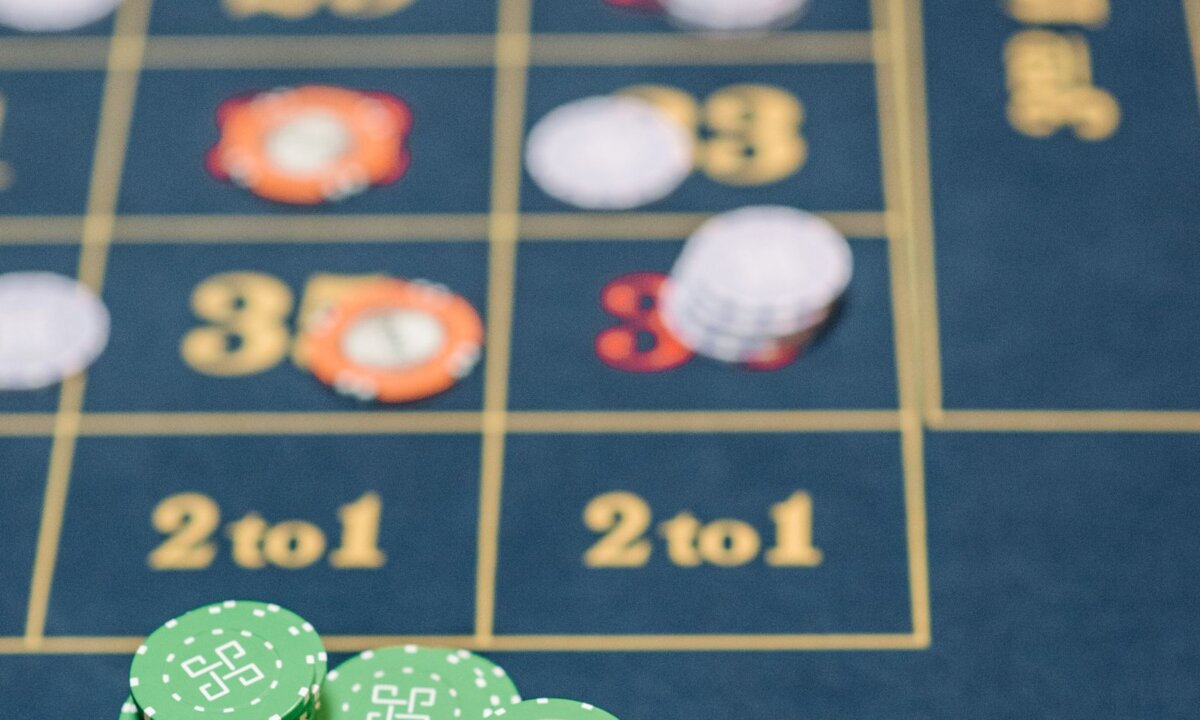 Small casino chip stacks positioned on a roulette layout for an NZD deposit plan