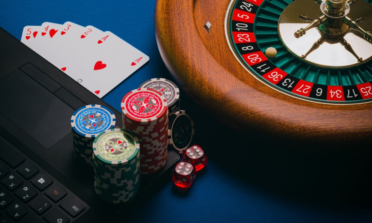 Laptop beside roulette chips cards and dice for an online NZ casino cashier route